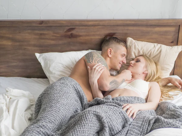 Ευτυχισμένο ζευγάρι φλερτ και μιλώντας το πρωί σε ένα άνετο κρεβάτι στο σπίτι ή δωμάτιο ξενοδοχείου. Έννοια της άνεσης και της αγάπης — Φωτογραφία Αρχείου