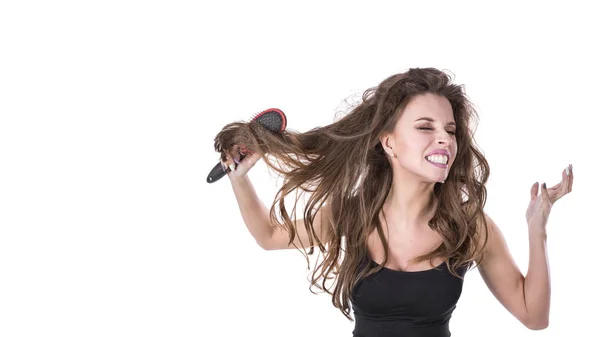 Linda chica saca un peine de pelo enredado y grita en la cámara sobre un fondo blanco. Concepto de salud del cabello . — Foto de Stock