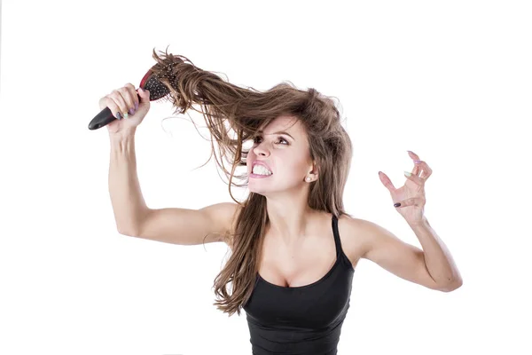 Linda chica saca un peine de pelo enredado y grita en la cámara sobre un fondo blanco. Concepto de salud del cabello . — Foto de Stock