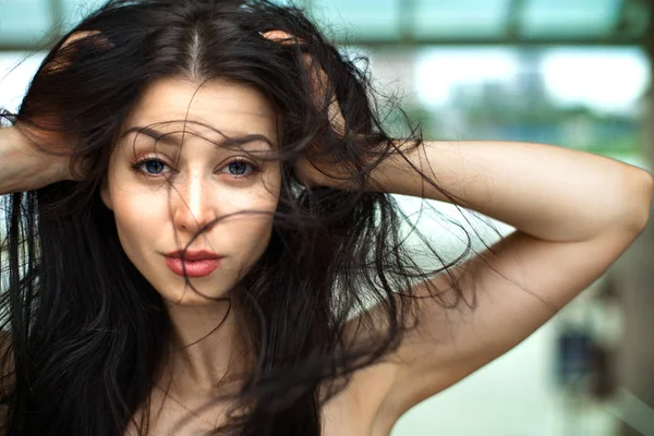 Mujer con el pelo soplando en el viento con un fondo de naturaleza borrosa, peinado natural, al aire libre — Foto de Stock