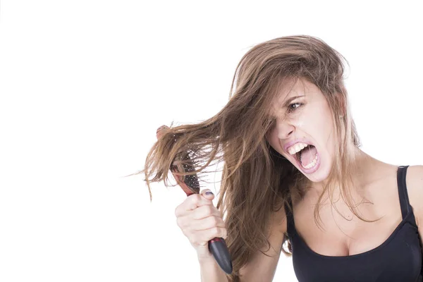 Mujer joven gritando mientras peina el pelo castaño por cepillo. Aislado sobre fondo blanco — Foto de Stock