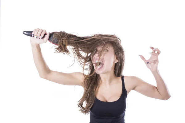 Mujer joven gritando mientras peina el pelo castaño por cepillo. Aislado sobre fondo blanco — Foto de Stock