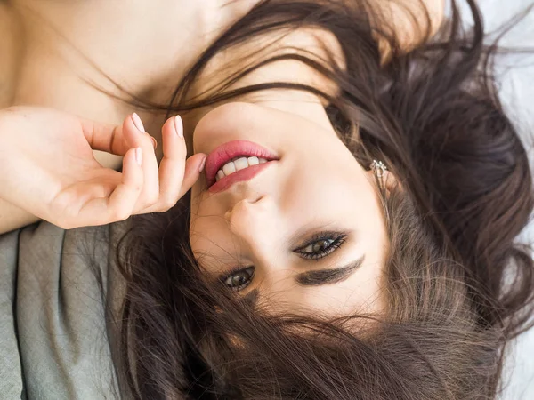 Close-up portrait of a girl with stunning dark hair, lying and looking at camera. Skin care concept — Stock Photo, Image