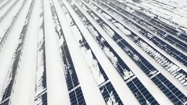 AERIAL: Fotovoltaico no inverno coberto de neve. Painéis solares entre os desvios de neve, cobertos de neve. Fontes de energia alternativas nos países nórdicos . — Vídeo de Stock