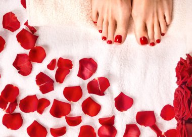 Spa ve sağlıklı yaşam. Terry havlu üzerinde gül yaprakları ile kadın ayakları.