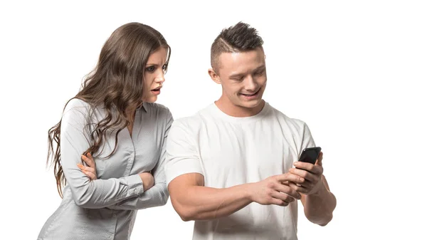 カップルの肖像画彼の携帯電話を探している男。腕を組んで怒った女性は、彼の携帯電話で彼の肩の上を見て. — ストック写真
