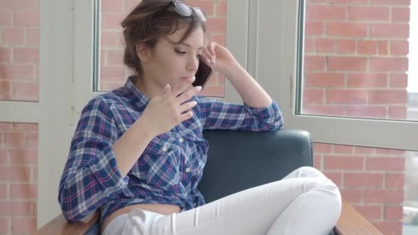 Vidám fiatal nő beszél mobilon otthon — Stock videók