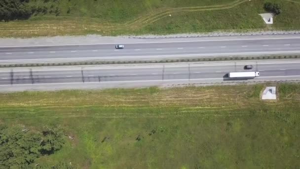 Vista aérea de la carretera en medio de la zona del parque en verano. Drone cinematográfico disparó volando sobre la carretera con el tráfico — Vídeo de stock