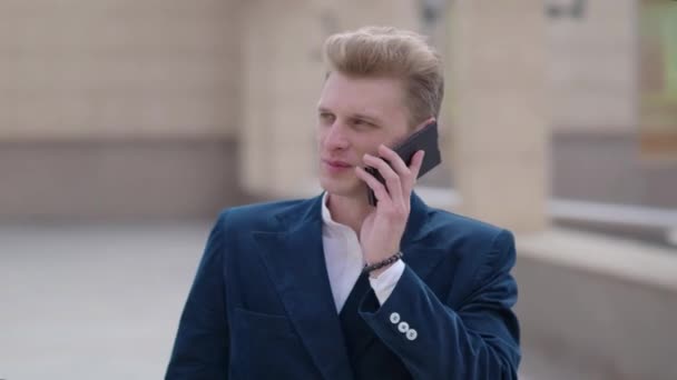 Мужчина со смартфона звонит на мобильный телефон ночью в городе. Красивый молодой бизнесмен, разговаривающий по смартфону, счастливо улыбающийся в пиджаке на улице. Профессионал городского типа в возрасте 20 лет — стоковое видео