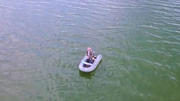 Visser blijven in een rubberboot op het meer bij dageraad in de zomer. Ochtend mist kruipt over het water. Schieten met quadrocopter vliegt laag over het water. — Stockvideo