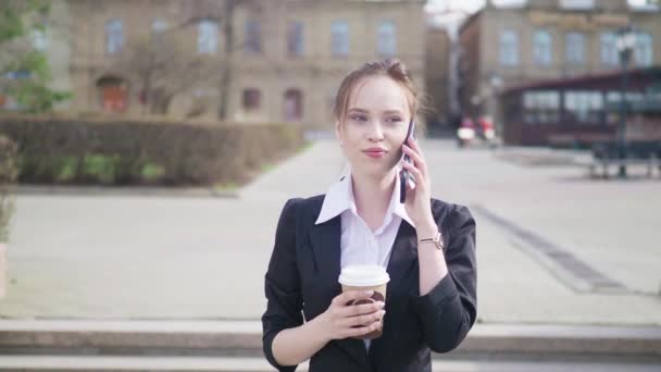 Zakenvrouw in stad met behulp van slimme telefoon met afhaalmaaltijden koffie — Stockvideo