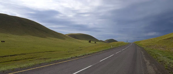 Weg tussen de heuvels. En prachtige bewolkte hemel. — Stockfoto