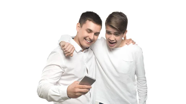 Dois homens alegres conversando e olhando para o telefone celular e rir, isolado sobre fundo branco . — Fotografia de Stock