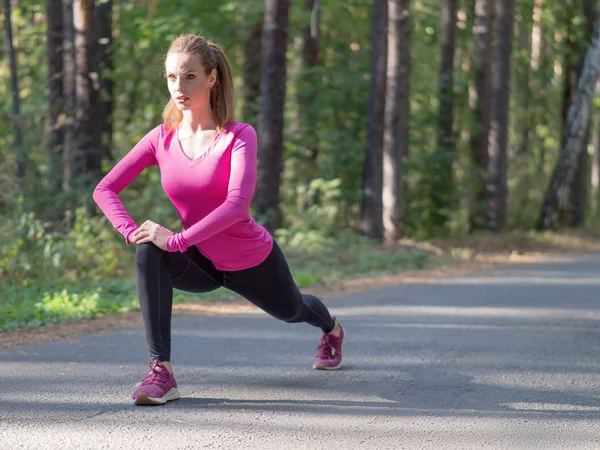 Mujer pelirroja estira los músculos en el parque antes de correr . — Foto de Stock