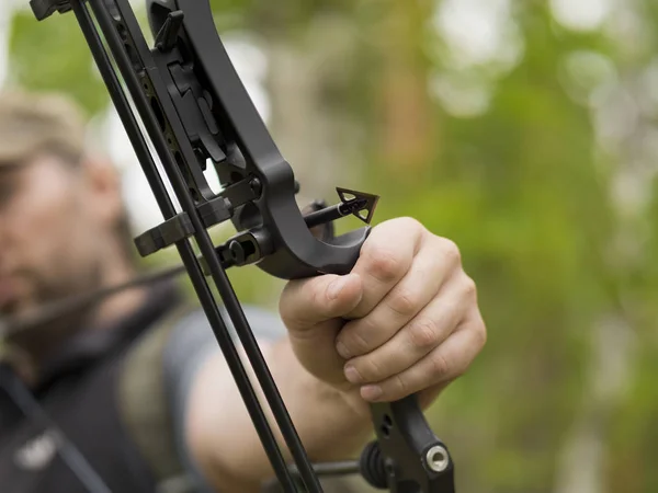 Man hunts in the forest with a bow. The hunter aims. Focus on sharp arrowhead — Stock Photo, Image