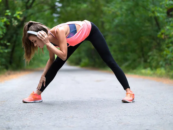 Hermosa mujer joven streth músculos antes de trotar en el bosque . — Foto de Stock