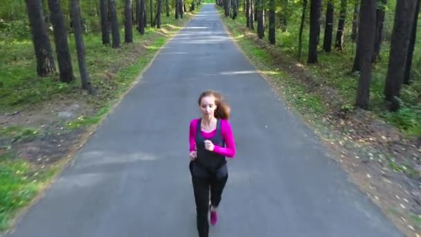 Una donna corre attraverso la foresta su una strada diritta. Giovane donna corre attraverso la foresta — Video Stock
