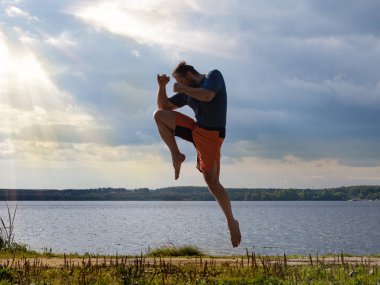 Açık havada bir kickboks trensilueti. Adam bir atlama diz tekme yapmak