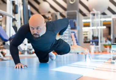 Acımasız sakallı adam fitness salonunda bir eliyle push up egzersiz yapıyor. Portreyi kapat