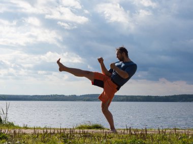 Açık havada bir kickboks trensilueti. Adam bir ön tekme yapmak