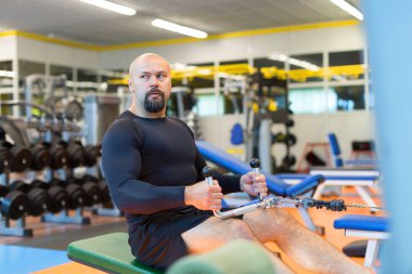 Orta yaşlı atlet bir spor kulübünde güç egzersiz makinesi ile bir sırt üzerinde egzersiz yapıyor.