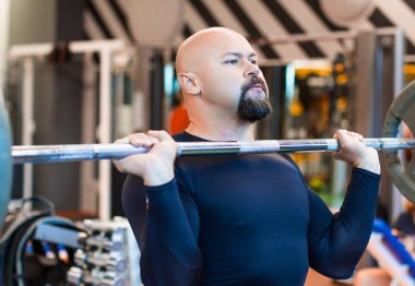 Vahşi orta yaşlı adam spor salonunda bir halter kaldırma.