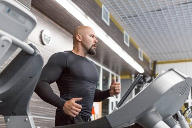 Spor salonunda koşu bandında koşan acımasız orta yaşlı adam.