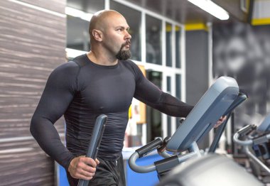 Spor salonunda bir fitness makinesi üzerinde orta yaşlı bir adam egzersiz Yan görünüm portresi