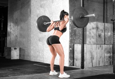 Spor salonundaki bir kadının yan görüntüsü. Çömelme