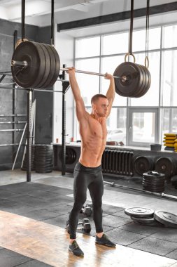 Spor salonunda bir bar eşliğinde halterli bir adam. Güçlü erkek antrenmanından spor salonu ağırlık kaldırma çubuğu