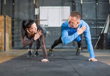 Fitness çifti spor yaparken ellerini güçlendiriyor. Erkek ve kadın spor salonunda çalışıyor.