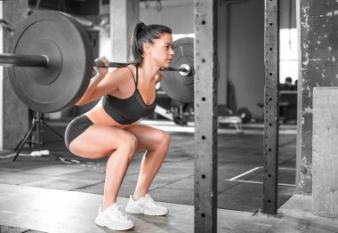 Spor salonundaki bir kadının yan görüntüsü. Sıkı antrenman. Çömel..