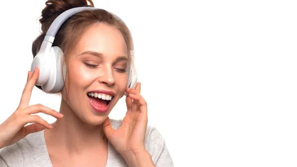 Menina atraente cantando com fones de ouvido no fundo branco — Fotografia de Stock