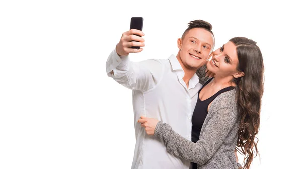 Jovem casal abraçando e sorrindo ao fazer selfie, de pé sobre fundo isolado branco . — Fotografia de Stock