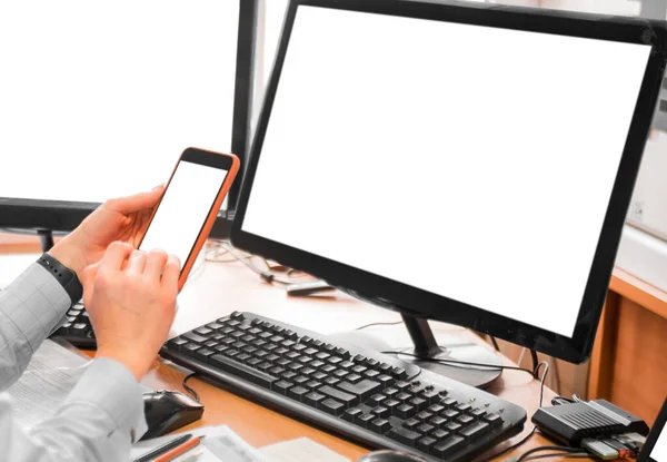 Kvinnan på kontoret framför monitorerna. Närbild av en hand med en telefon. — Stockfoto