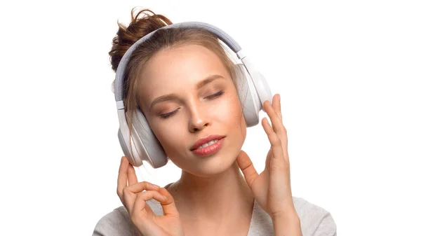 Fille attrayante avec les yeux fermés écoutant la musique via un casque sur fond blanc — Photo