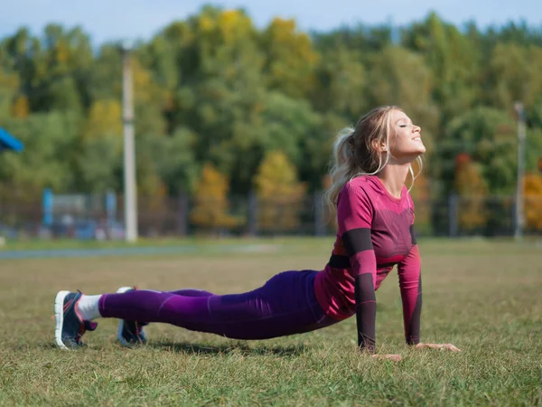 Mujer haciendo ejercicios de yoga y estirándose en la hierba al aire libre en un parque . — Foto de Stock