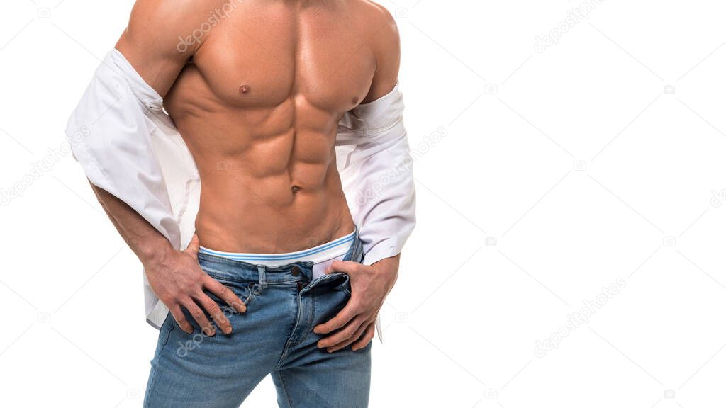 Sexy man in blue jeans and white shirt touching his perfect abs. Isolated on white.