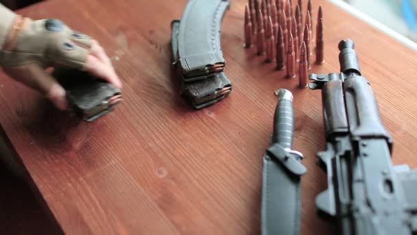 De hand van een soldaat of terrorist legt munitie op tafel. — Stockvideo