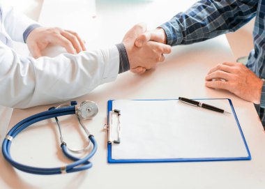 Hasta ve doktor, sağlık sigortası sözleşmesi imzaladıktan sonra el sıkışıyor..