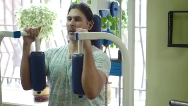 Homme d'âge moyen faisant de l'exercice sur une machine à papillon thoracique. Vue latérale . — Video
