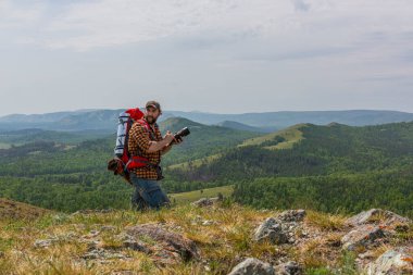 Dağın tepesinde kamerası olan bir adam. Vahşi yaşam fotoğrafçısı iş başında.