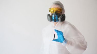 Beyaz önlüklü doktor ve solunum cihazıyla test tüpündeki kan örneğini uluyan doktor.