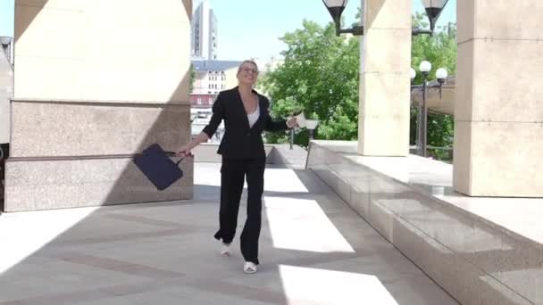 Happy business lady celebrates something and dances while walking along the city street — Stock Video