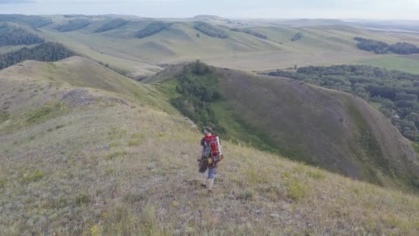 La telecamera segue un escursionista con uno zaino che corre lungo la cima della collina. — Video Stock