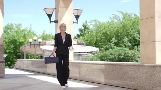 Slow motion - happy businesswoman celebrates something and dances while walking along the city street — Stock Video