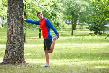 Koşucu adam dışarıda kaslarını esnetiyor. Spor ve sağlıklı yaşam tarzı kavramı..