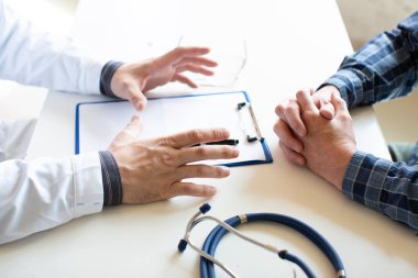 Doktor ve hastanın elleri, yakın plan. Sağlık sigortası belgelerinin imzalanması.