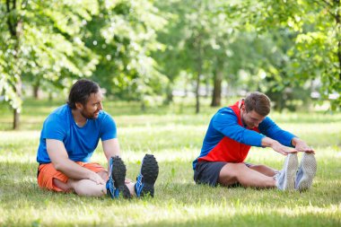 Dışarıda koştuktan sonra kaslarını esneten iki adam..