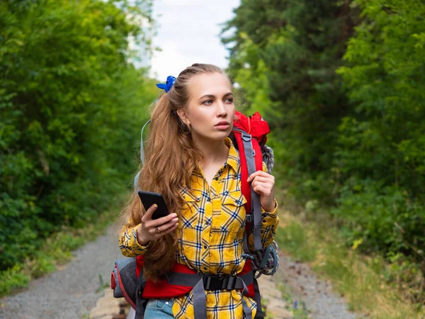 Portret van een vrouw die verloren is in het bos. Ze gebruikt mobiele GPS-kaart. — Stockfoto